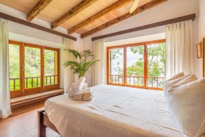 a bedroom with a large white bed with windows at Es Racó d'Alconàsser in Sóller +29 photos