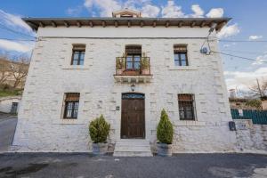 a white stone building with a wooden door at La Morada del Cura in Calabazas