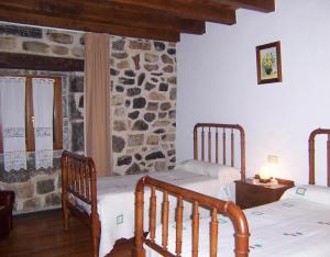 a bedroom with two beds and a stone wall at Casa Rural Barbonea in Lekunberri