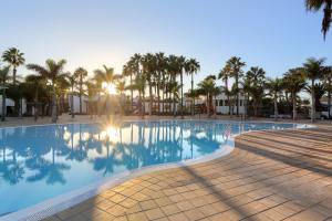 a swimming pool with palm trees in the background at Casa de la Calma in Corralejo +21 photos