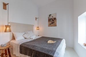 a white bedroom with a bed with a cat on it at Lithos in Kóstos