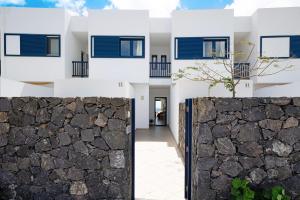 a house with white walls and a stone fence at Malvasia 22 in Puerto Calero
