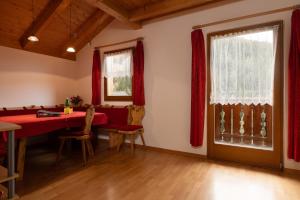 a dining room with a red table and a window at Apt Bergblick Hinterproslhof in Sarntal
