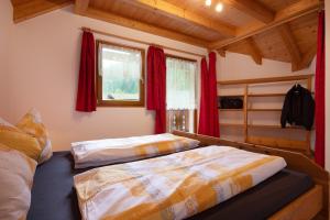 two beds in a bedroom with red curtains at Apt Bergblick Hinterproslhof in Sarntal