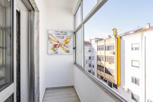 a hallway with a window and a butterfly clock on the wall at Sleeptubal Moderne Accommodatie in Alhos Vedros