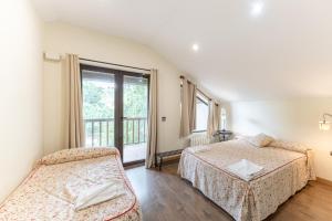 a bedroom with two beds and a window at El Herrén Del Abuelo in Vegas de Matute