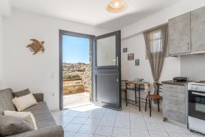a living room with a kitchen and a door with a view at Anastasias Studios Mykonos in Plintri