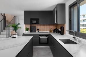 a kitchen with black cabinets and white counter tops at Penthouse Apt With Ocean View in Estepona