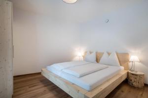 a bedroom with a wooden bed with white walls at Naturapartments Alpreid Altholz in San Pancrazio dʼUltimo