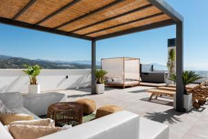 a patio with a white couch and chairs on a roof at Penthouse Apt With Ocean View in Estepona