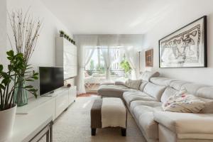 a white living room with a couch and a tv at Canet Platja Apartment in Canet de Mar