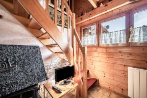 a living room with a staircase and a television in a cabin at Chalet 4p Simple - La Gélinotte in Verchaix
