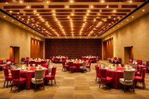 a banquet hall with red tables and chairs and lights at The Weekend Address Managed By Stayzy in Dumas +9 photos