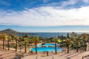 a view of a pool with palm trees and the ocean at Appartement Cap Esterel St Raphaël in Saint-Raphaël