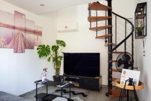 a living room with a television and a spiral staircase at Lucerta Bella in Aix-en-Provence