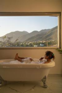 a woman laying in a bath tub in a window at Perfectstayz Premium Dehradun at Rajpur road in Dehradun