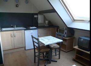 a kitchen with a table and chairs and a sink at Les Orchidées - chambres d'hôtes in Surtainville
