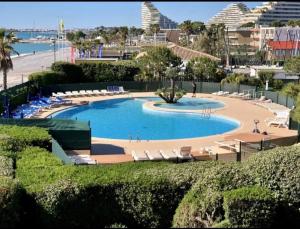a large swimming pool with chairs and a beach at Studio Riviera de Bahia in Villeneuve-Loubet