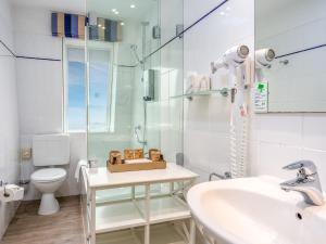 ein weißes Badezimmer mit Waschbecken und Toilette in der Unterkunft PLAZA Premium Sylt in Wenningstedt-Braderup