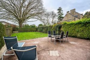 a patio with a table and chairs in a yard at Gite Palombe in Lanvallay