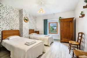 a bedroom with two beds and a window at Gite Palombe in Lanvallay
