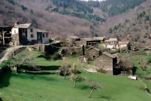 an old house in a green field with mountains in the background at Chambre Bleue - Ostau la Lutz in Saint-Germain-de-Calberte