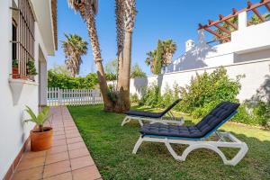 a patio with two lounge chairs and palm trees at Casa Dos Mares in Cádiz