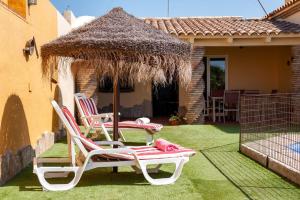 two lawn chairs sitting on the grass in front of a house at Chalet Rocío - solo familias in Conil de la Frontera