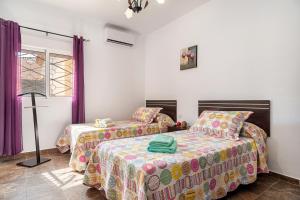 a bedroom with two beds and purple curtains at Chalet Rocío - solo familias in Conil de la Frontera +17 photos