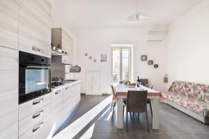 a white kitchen with a table and a couch at Casa Vacanze Lu Rizzaru in Nardò