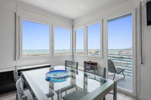 a dining room with a table and chairs and windows at Vora Port in L'Ampolla