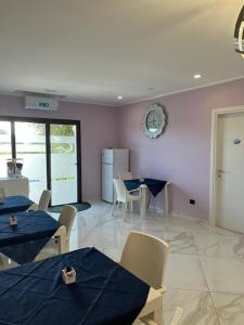 a dining room with tables and chairs and a clock on the wall at Mare Azzurro in Marina di Camerota