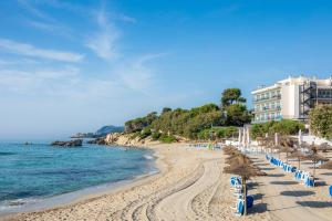 a beach with blue and white chairs and a building at Na Forana in Cala Ratjada
