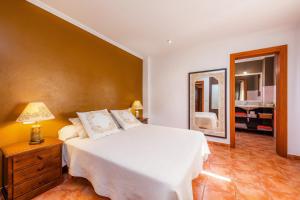 a bedroom with a white bed and a mirror at Na Forana in Cala Ratjada
