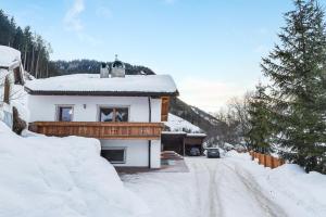a house is covered in snow on a snowy road at Apt Hetti - Haus Kostner in Santa Cristina Gherdëina