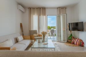 a living room with a couch and a glass table at Joan Serenity Apartment in Porto Heli