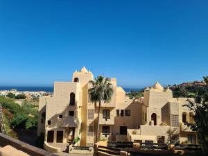 a house with a palm tree in front of it at Superb 2-bed apartment in Duquesa in Manilva