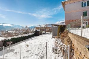 a building with snow on the ground next to a fence at Casa Zarina Well-kept Two-room in Cavalese