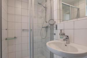 a white bathroom with a sink and a shower at Fewo Blick über Sylt in Westerland