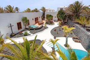 an external view of a resort with a pool and palm trees at Villa La Cueva in Teguise