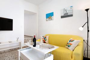 a living room with a yellow couch and a white table at Casa Rincón del Beso in Vejer de la Frontera