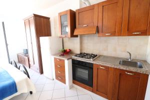 a kitchen with wooden cabinets and a stove top oven at Casa vacanze Frida in Salento in Otranto +24 photos