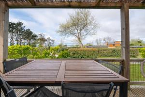 a wooden table and chairs on a deck with a view at Chalet 25m2 - La Vieille in Plouhinec