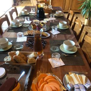 a long wooden table with bread and coffee on it at Suite familiale - Gîte du Moulin in La Noue