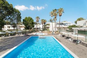 a pool with chairs and umbrellas in front of a building at Casa Noa in Costa Del Silencio