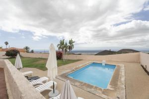 a swimming pool with two lawn chairs and umbrellas at Casa El Pinito No Groups Under 27 in Tamaide