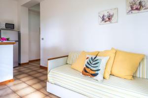 a couch in a living room with yellow and white pillows at Villa Vanna Bilo A - bilocale in Capoliveri