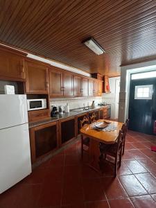 a kitchen with a table and a white refrigerator at Desterro House in Angra do Heroísmo