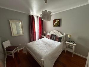 a bedroom with a white bed and a chair at Desterro House in Angra do Heroísmo