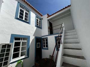a white house with blue doors and stairs at Desterro House in Angra do Heroísmo